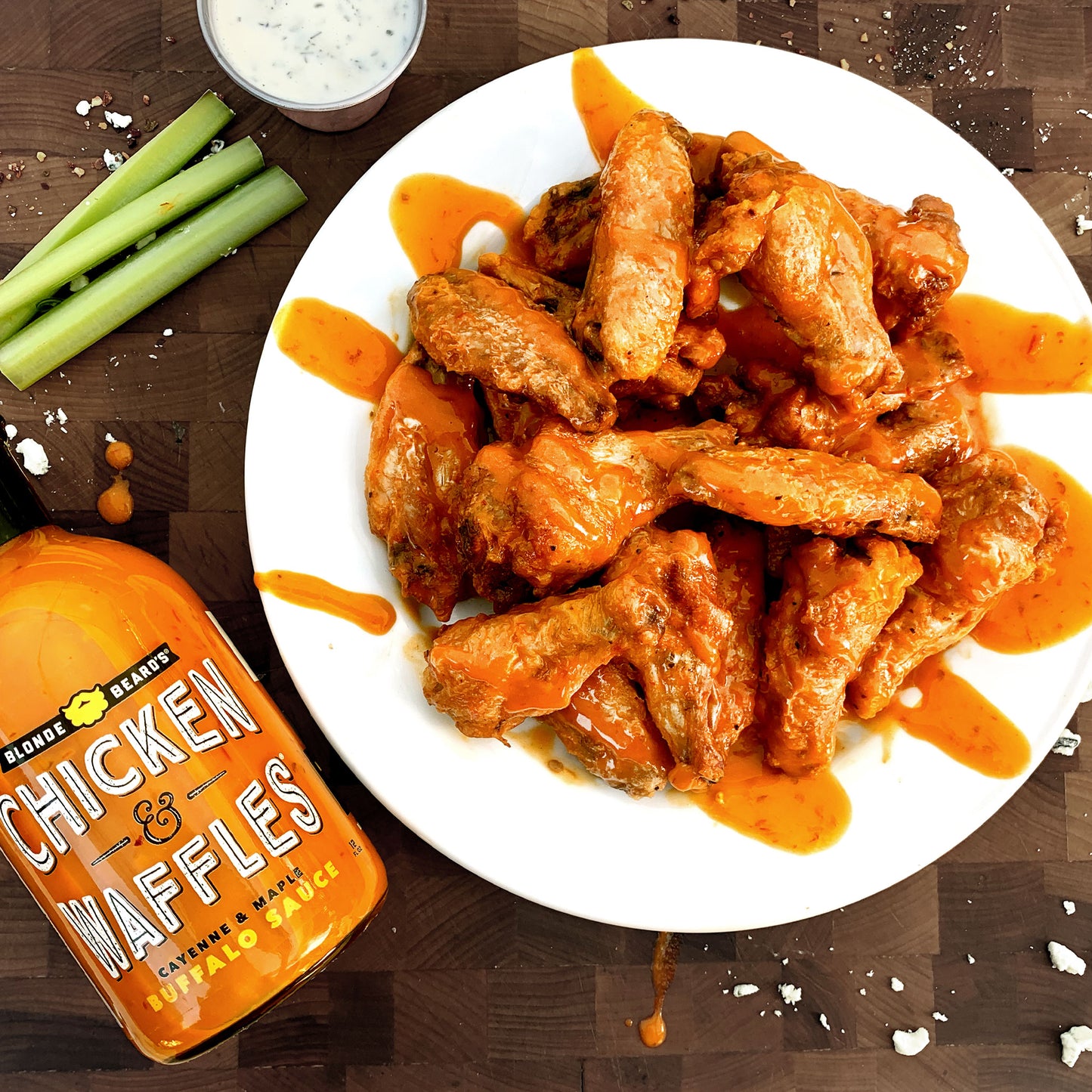 Chicken and waffles served alongside a plate of buffalo wings made with Chicken & Waffles buffalo wing sauce.